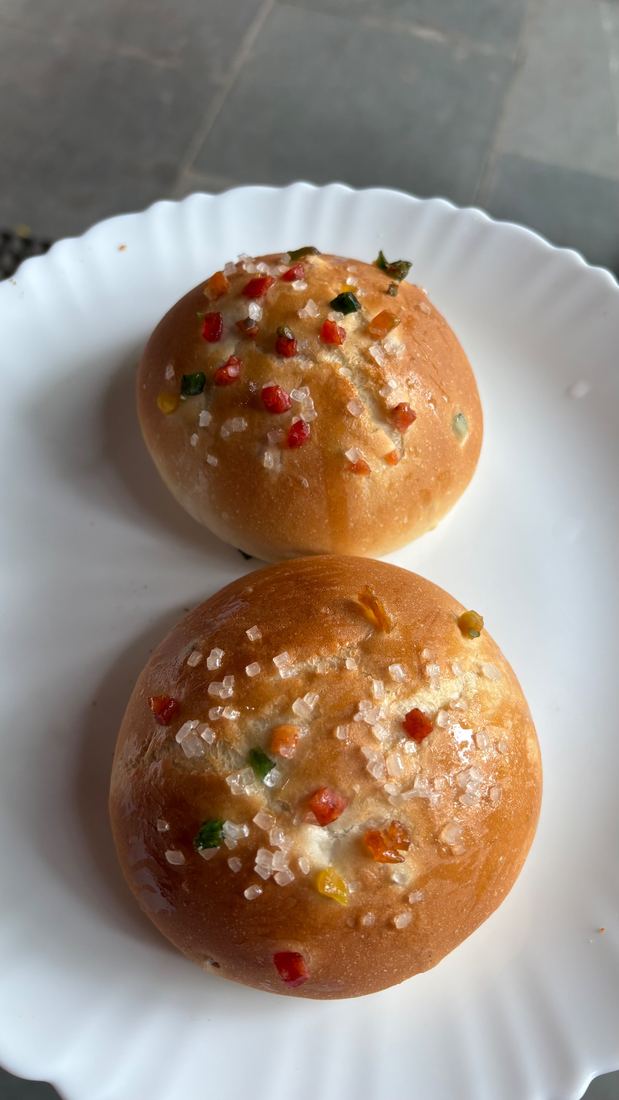 Two glossy buns topped with colourful candied fruit and sugar crystals